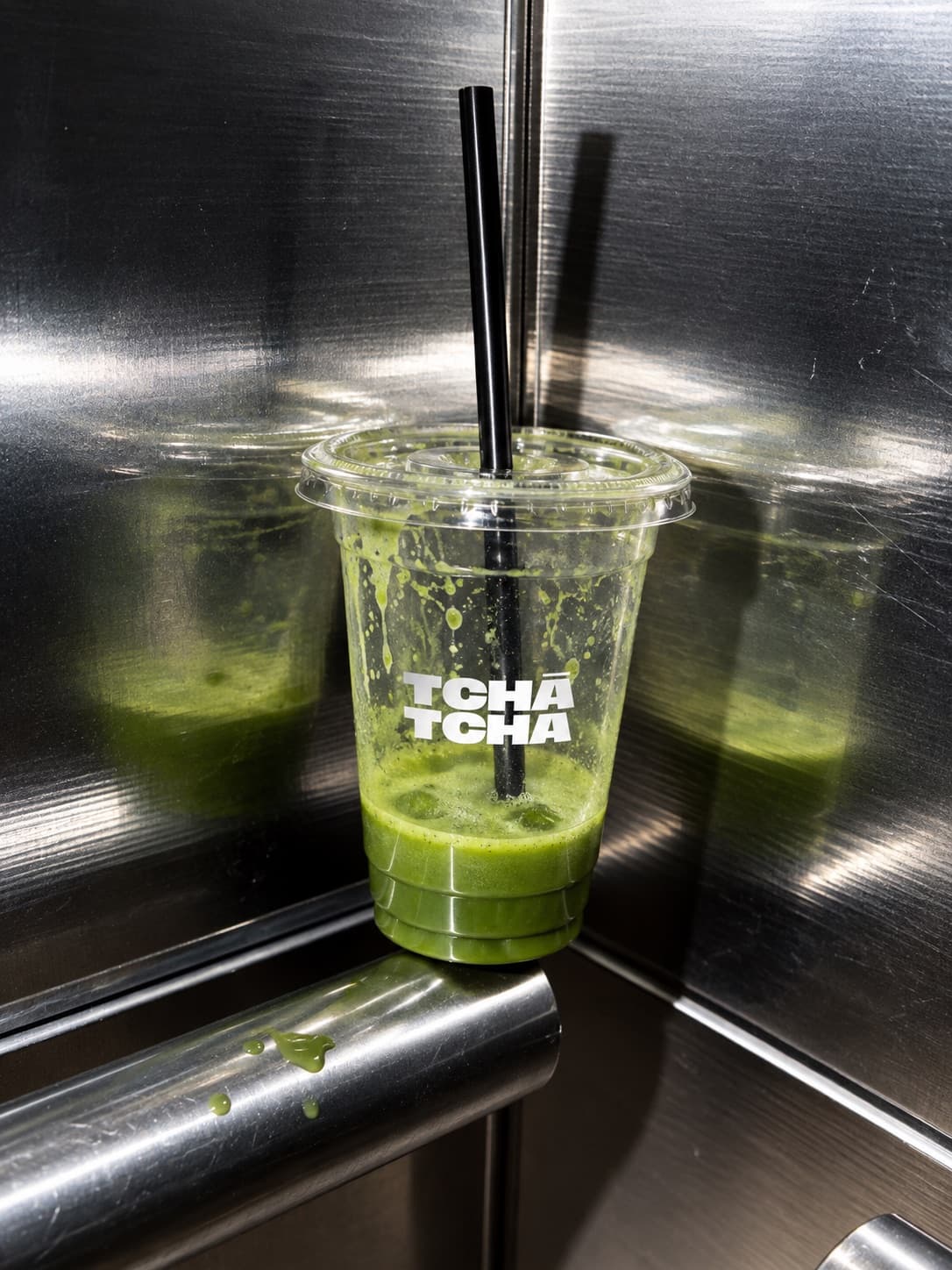 Copo de matcha gelado ao canto de um elevador de aço